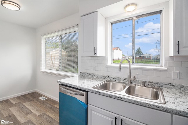 kitchen with visible vents, wood finished floors, a sink, white cabinets, and dishwashing machine