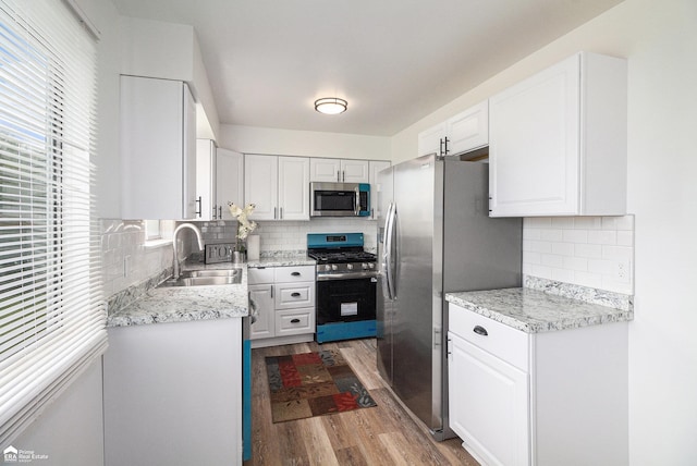 kitchen featuring white cabinetry, appliances with stainless steel finishes, a sink, and wood finished floors