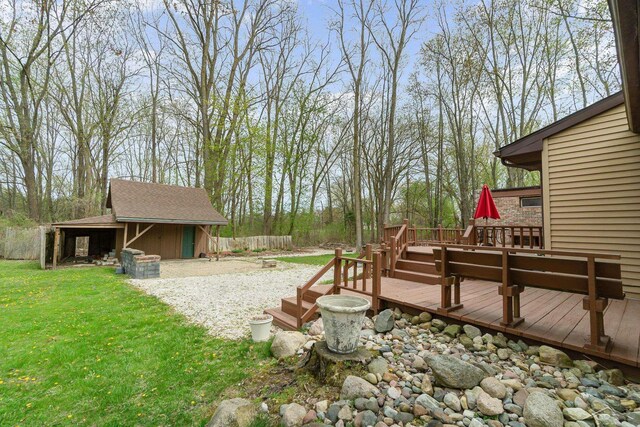 view of yard featuring a storage shed, fence, a wooden deck, and an outdoor structure