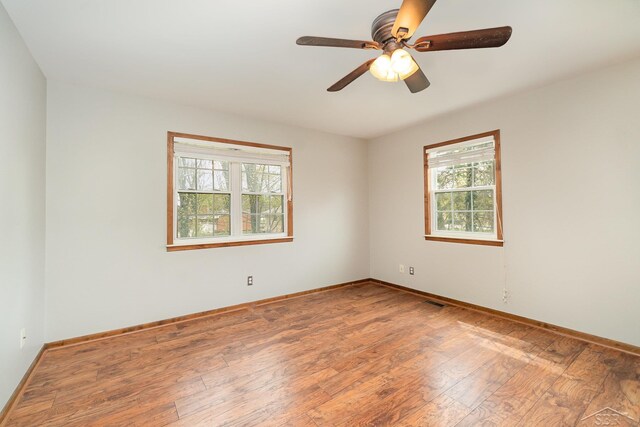 unfurnished room featuring baseboards, ceiling fan, a healthy amount of sunlight, and hardwood / wood-style floors