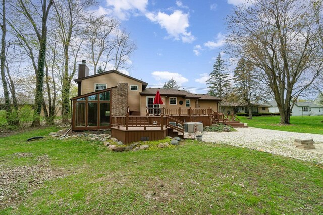 rear view of property with a sunroom, a yard, a chimney, and a deck
