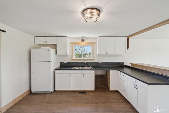 13280 Burt Rd, Pittsford, MI 49271 - kitchen with freestanding refrigerator, white cabinetry, dark countertops, and a sink
