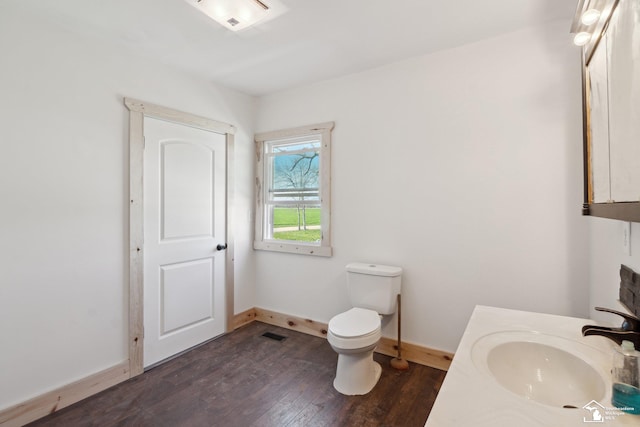 13280 Burt Rd, Pittsford, MI 49271 - half bath with visible vents, wood finished floors, baseboards, vanity, and toilet