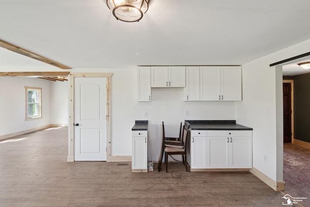 13280 Burt Rd, Pittsford, MI 49271 - kitchen with white cabinets, dark countertops, baseboards, and wood finished floors