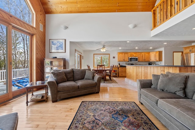 7734 N Shore Ct, Grawn, MI 49637 - living room with ceiling fan, a towering ceiling, wooden walls, light wood-style floors, and recessed lighting