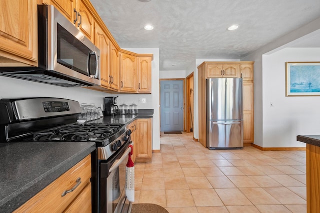 7734 N Shore Ct, Grawn, MI 49637 - kitchen with dark countertops, baseboards, stainless steel appliances, recessed lighting, and light tile patterned flooring