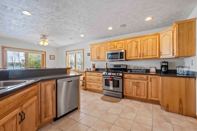 7734 N Shore Ct, Grawn, MI 49637 - kitchen with recessed lighting, dark countertops, appliances with stainless steel finishes, and light tile patterned floors