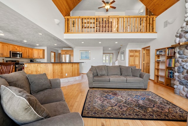 7734 N Shore Ct, Grawn, MI 49637 - living room with high vaulted ceiling, ceiling fan, and light wood finished floors