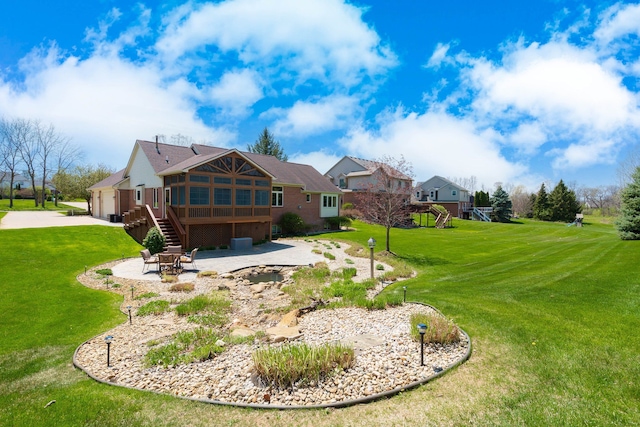 rear view of house featuring stairs, brick siding, a patio area, concrete driveway, and a yard