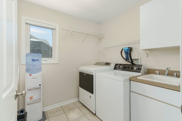 washroom with cabinet space, a sink, light tile patterned floors, baseboards, and washer and dryer