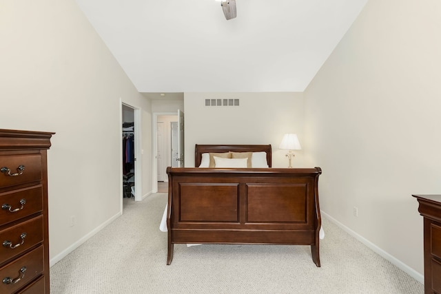 bedroom featuring light colored carpet, a walk in closet, a ceiling fan, baseboards, and visible vents