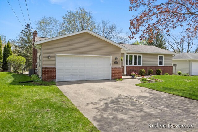 single story home featuring a chimney, brick siding, a front lawn, concrete driveway, and an attached garage