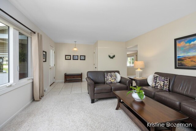 living area featuring baseboards, light tile patterned flooring, and light colored carpet