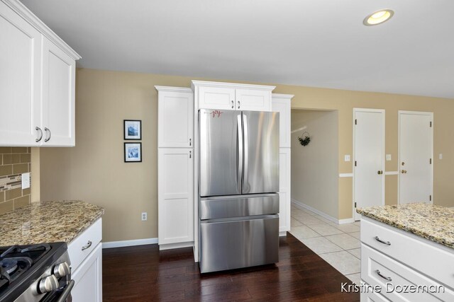 kitchen featuring white cabinetry, appliances with stainless steel finishes, light stone counters, and tasteful backsplash