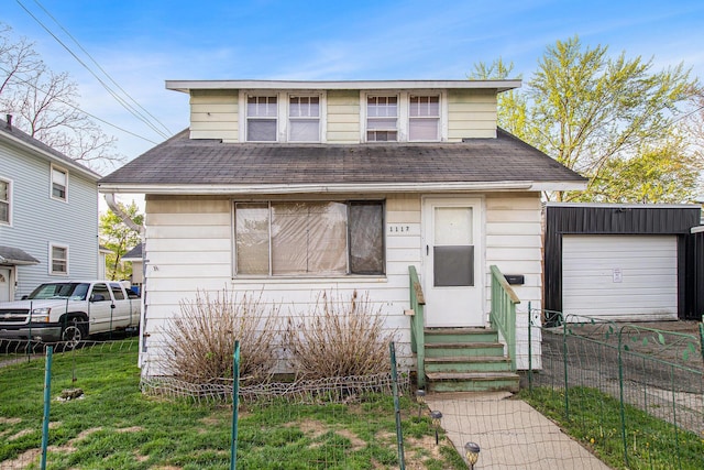 bungalow with fence, an outdoor structure, a front lawn, a shingled roof, and entry steps