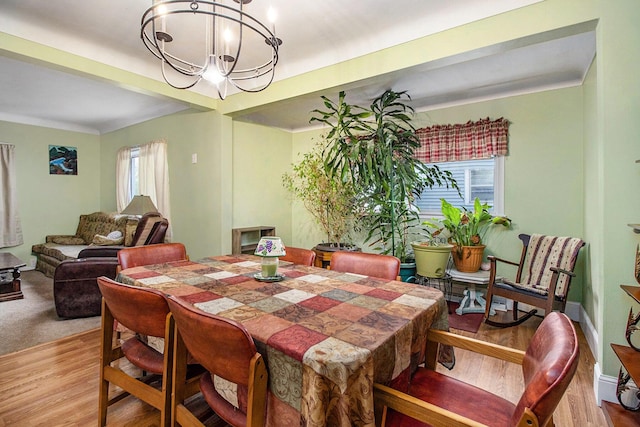 dining area with baseboards, wood finished floors, and a notable chandelier