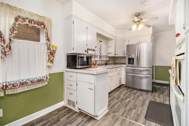 kitchen with light countertops, appliances with stainless steel finishes, a sink, and wood finished floors