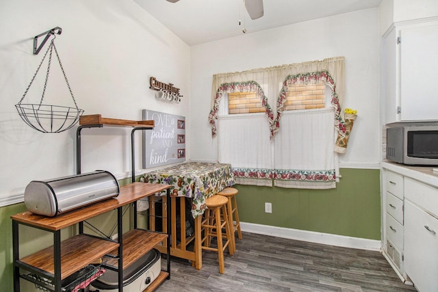dining space with baseboards, a ceiling fan, and wood finished floors