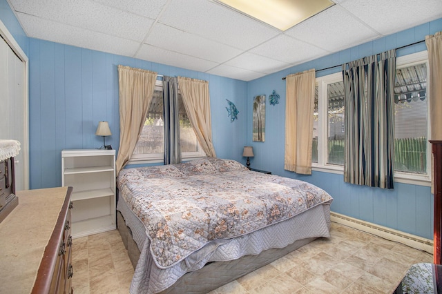 bedroom with a closet, a paneled ceiling, and a baseboard radiator