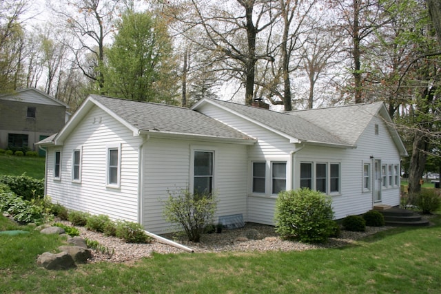 view of property exterior featuring a lawn, a shingled roof, and a chimney