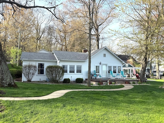 back of property featuring a lawn, a wooden deck, and roof with shingles