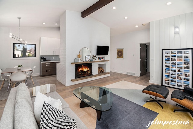 living area with visible vents, light wood finished floors, recessed lighting, vaulted ceiling with beams, and a lit fireplace