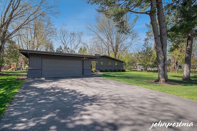 exterior space with board and batten siding, driveway, a chimney, a yard, and an attached garage