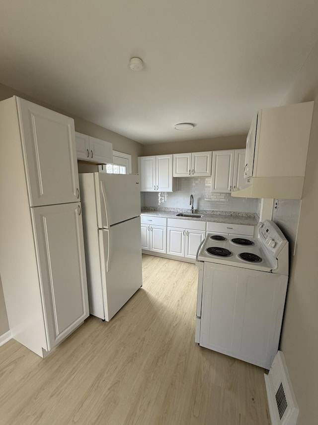 kitchen featuring visible vents, a sink, light countertops, white appliances, and white cabinetry