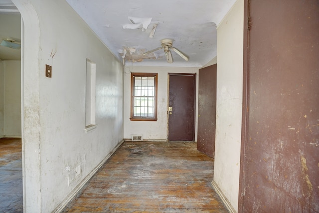 hallway with arched walkways, hardwood / wood-style flooring, and visible vents