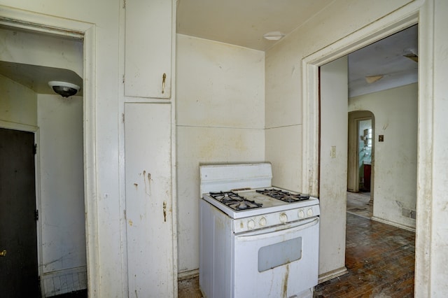 kitchen featuring wood-type flooring, arched walkways, and white range with gas cooktop