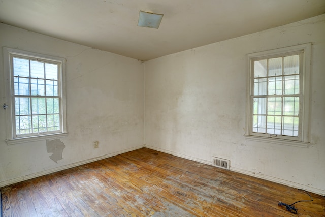 unfurnished room with visible vents, a healthy amount of sunlight, and hardwood / wood-style floors