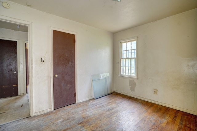 spare room with baseboards and hardwood / wood-style flooring