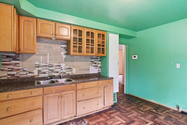 kitchen with a sink, backsplash, glass insert cabinets, and light brown cabinets