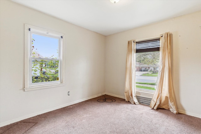 spare room with light carpet, healthy amount of natural light, and baseboards