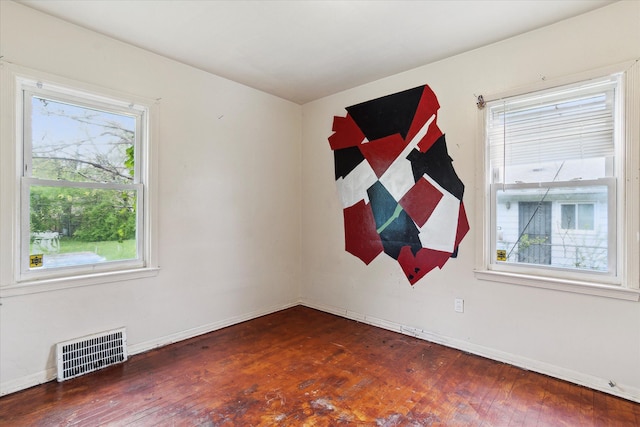 empty room featuring hardwood / wood-style flooring, plenty of natural light, and baseboards