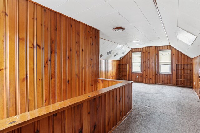 additional living space with wooden walls, carpet flooring, and lofted ceiling