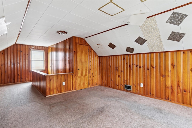 additional living space featuring vaulted ceiling, wood walls, and carpet