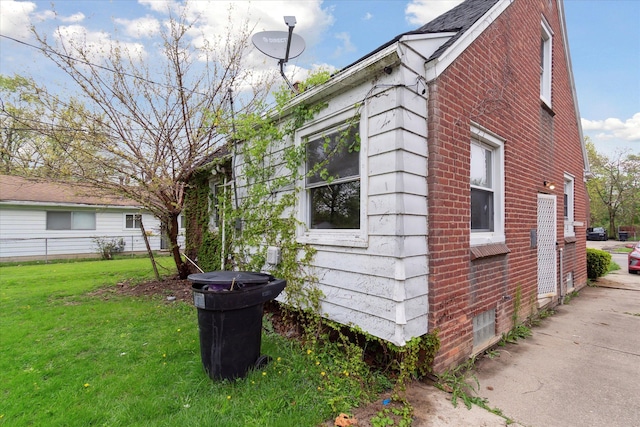 view of side of home featuring brick siding and a yard
