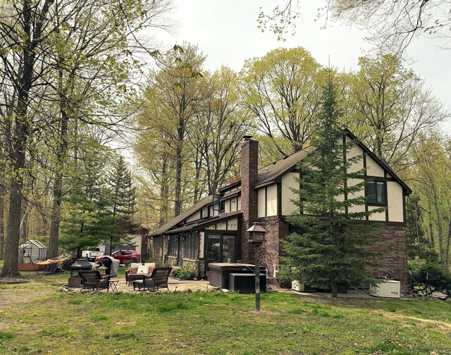 55535 Woody Ln, South Lyon, MI 48178 - back of house with brick siding, a yard, a patio, stucco siding, and a chimney