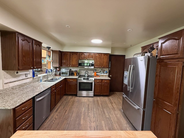 55535 Woody Ln, South Lyon, MI 48178 - kitchen with stainless steel appliances, a sink, wood finished floors, tasteful backsplash, and dark brown cabinets