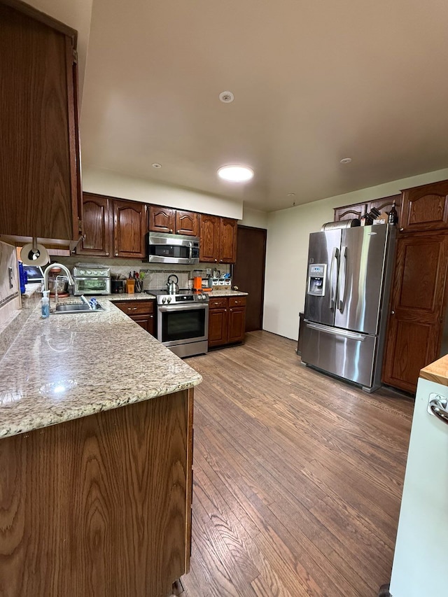 55535 Woody Ln, South Lyon, MI 48178 - kitchen featuring light wood-style flooring, dark brown cabinets, a sink, backsplash, and stainless steel appliances