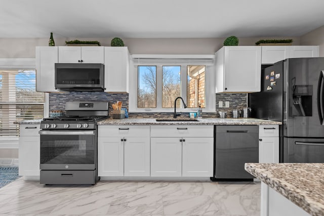 kitchen featuring a sink, light stone counters, white cabinets, black appliances, and marble finish floor