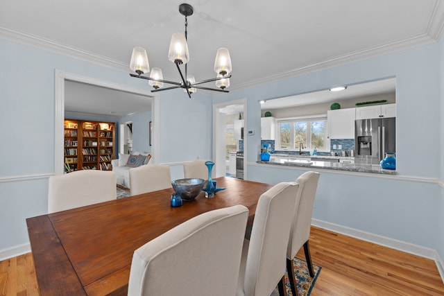 dining space featuring light wood-type flooring, ornamental molding, and a notable chandelier