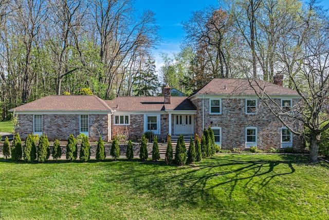 rear view of property featuring a lawn, a chimney, and brick siding