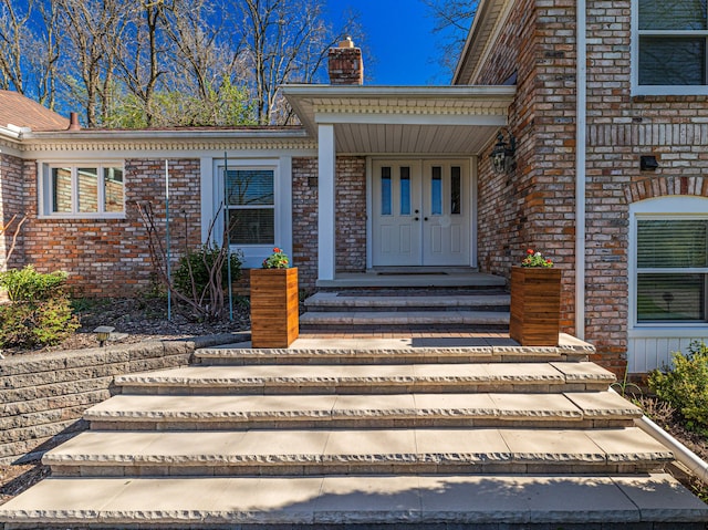 entrance to property featuring brick siding and a chimney