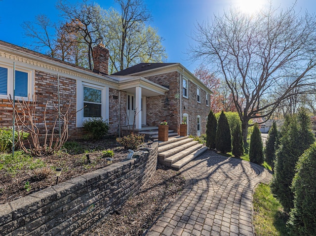 view of front of property featuring brick siding and a chimney