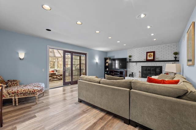 living room with recessed lighting, light wood-style flooring, and a brick fireplace