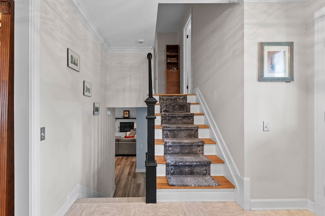 stairway with baseboards, ornamental molding, and a fireplace
