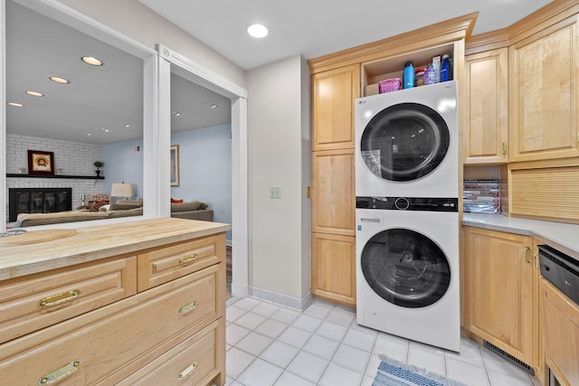 laundry room with light tile patterned flooring, stacked washer / drying machine, laundry area, a brick fireplace, and recessed lighting