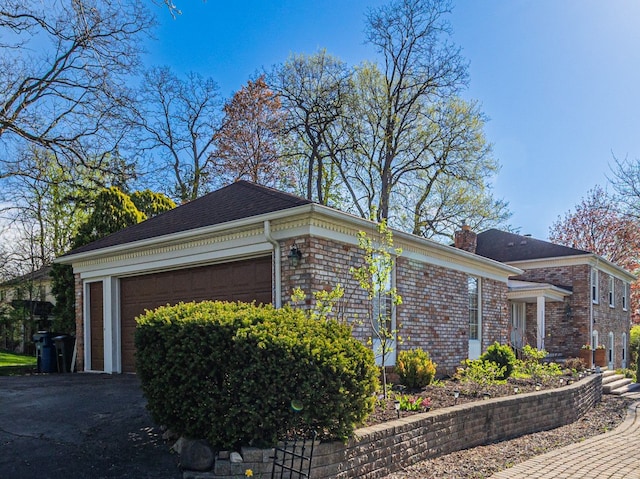 view of property exterior with a garage, a chimney, and brick siding